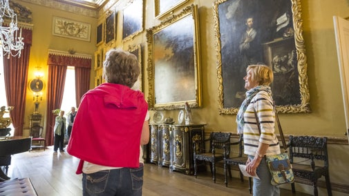 Two women looking at paintings on the walls of a large room